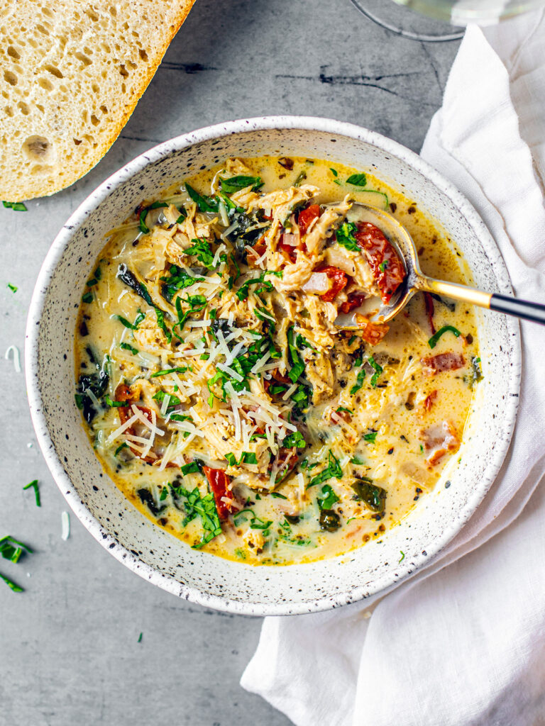 Bowl of chicken florentine soup next to a hunk of fresh bread.