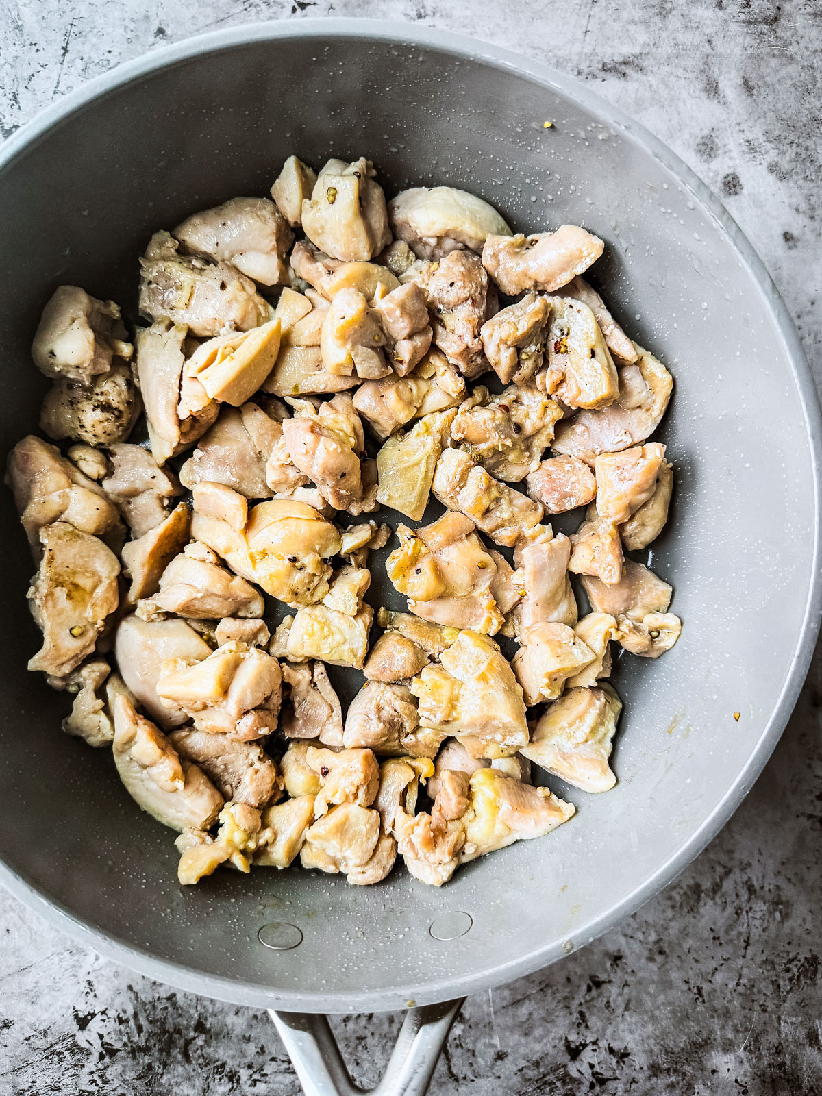 Diced chicken in a sauté pan.