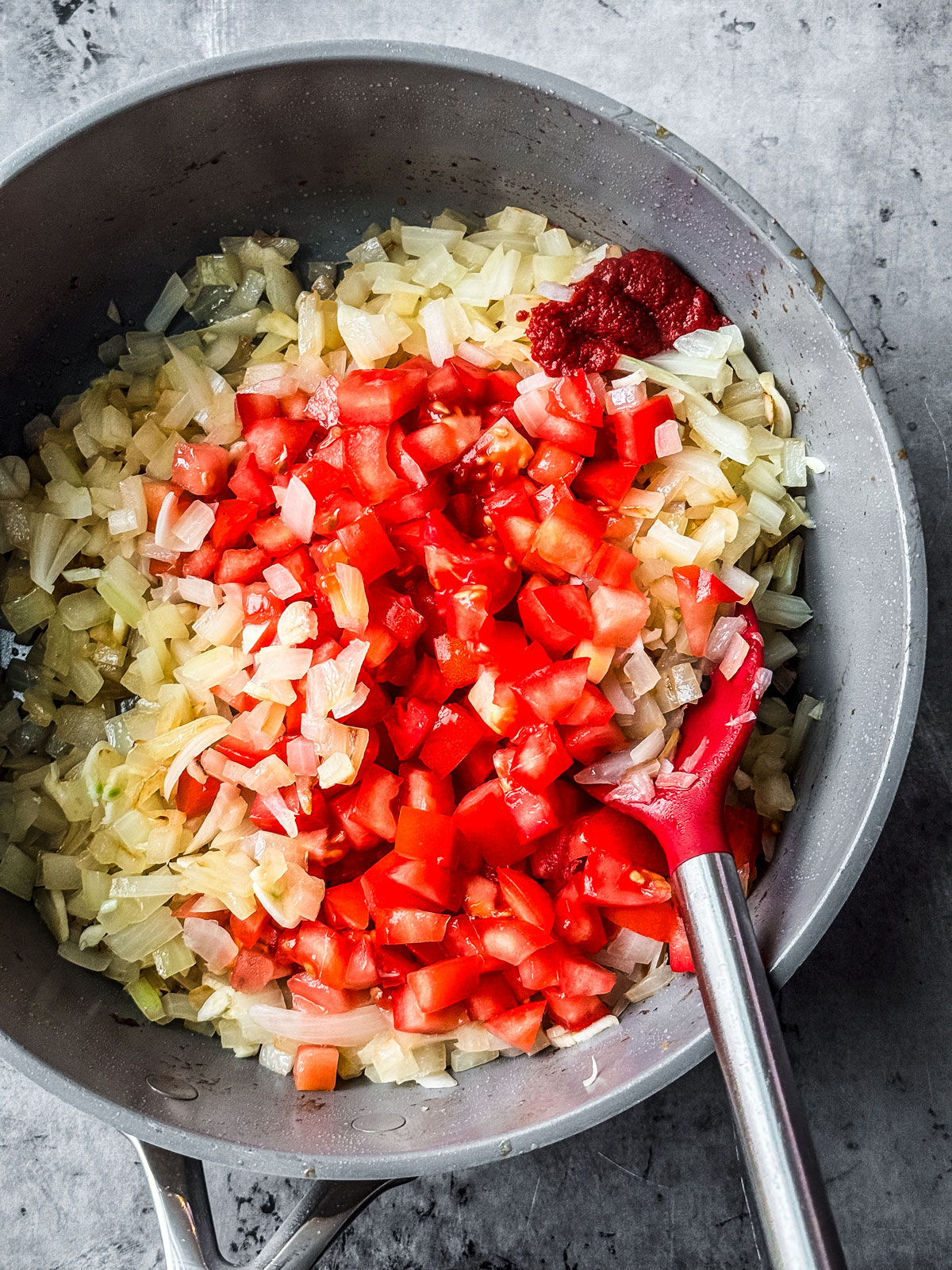 Onions and tomatoes being fried in a pan.