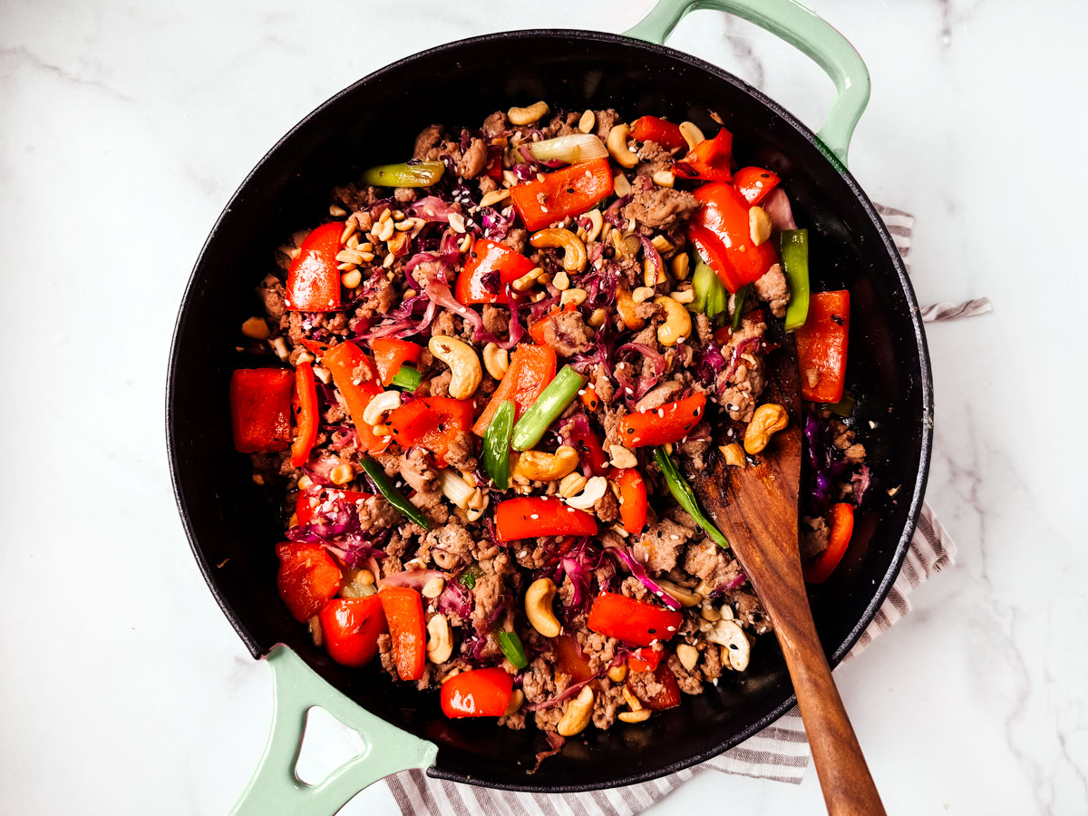 Ground turkey stir fry in a pan with cashews.