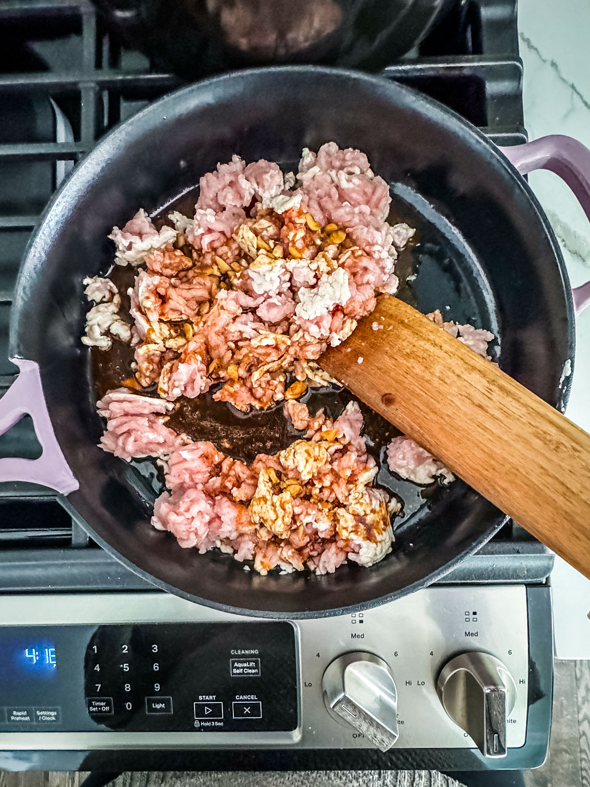 Half-cooked ground turkey in a pan with a bit of stir fry sauce.