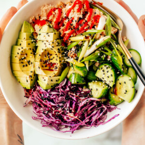 Hands holding up a bowl of canned tuna with various veggies.