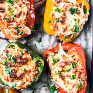 Baked cheesy stuffed peppers with ground turkey on a baking sheet.