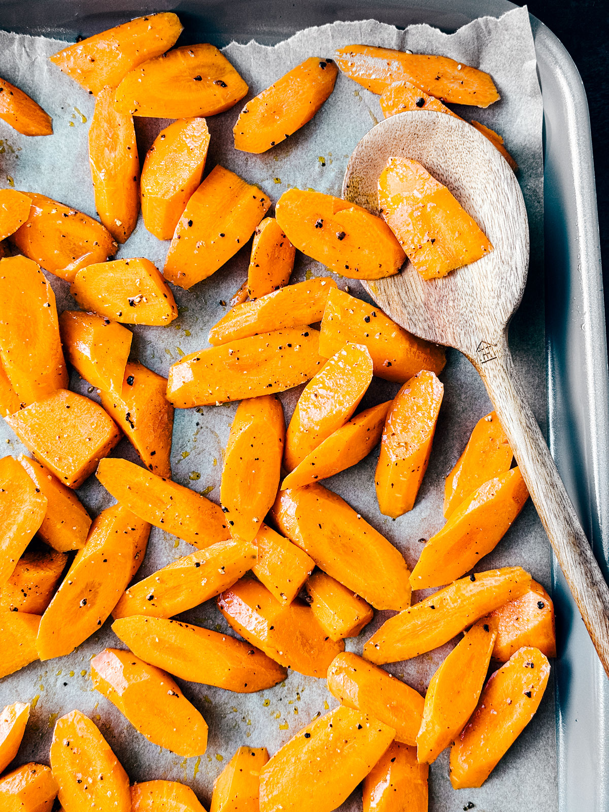 Sheet pan with carrots tossed in olive oil, salt, and pepper.