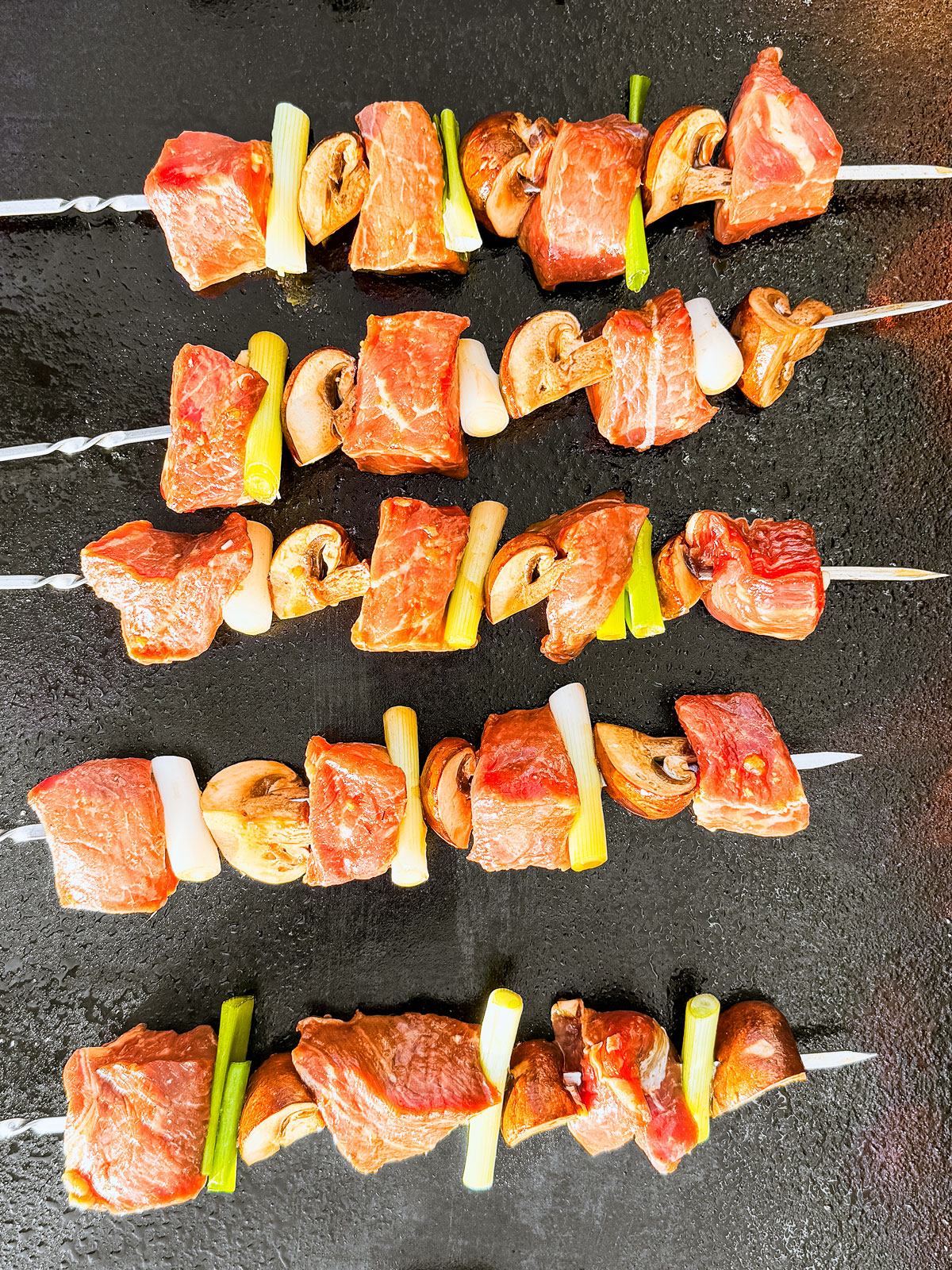 Beef skewers on a flat top grill.