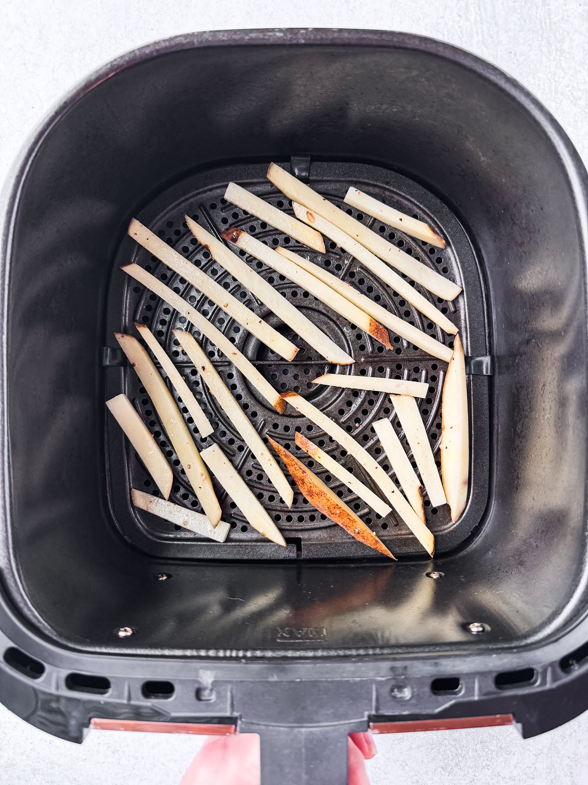 Uncooked fries placed in the air fryer basket.