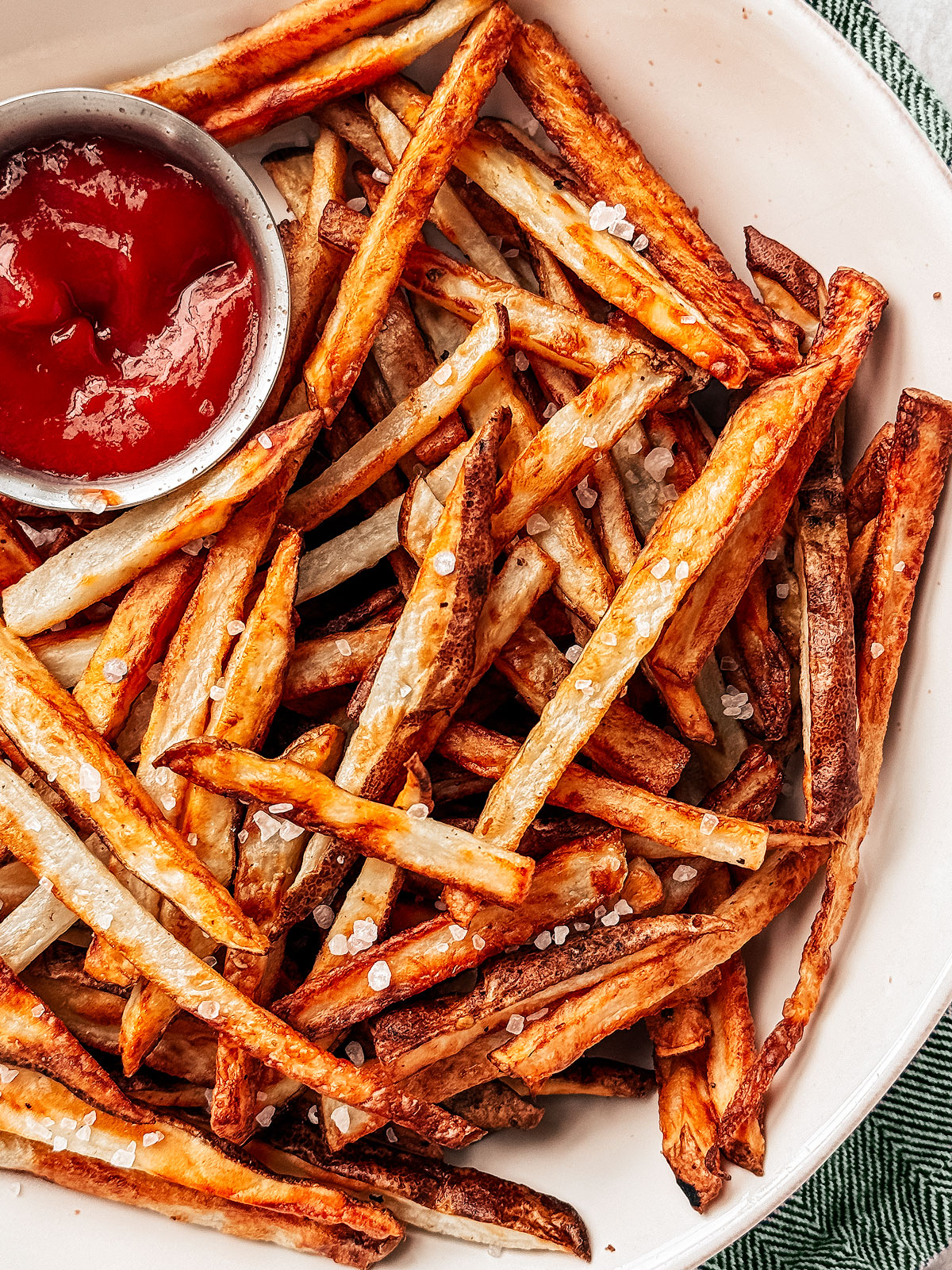 Serving bowl of air fryer french fries with ketchup on the side for dipping.