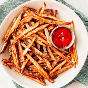 Serving bowl of air fryer French fries with ketchup on the side.