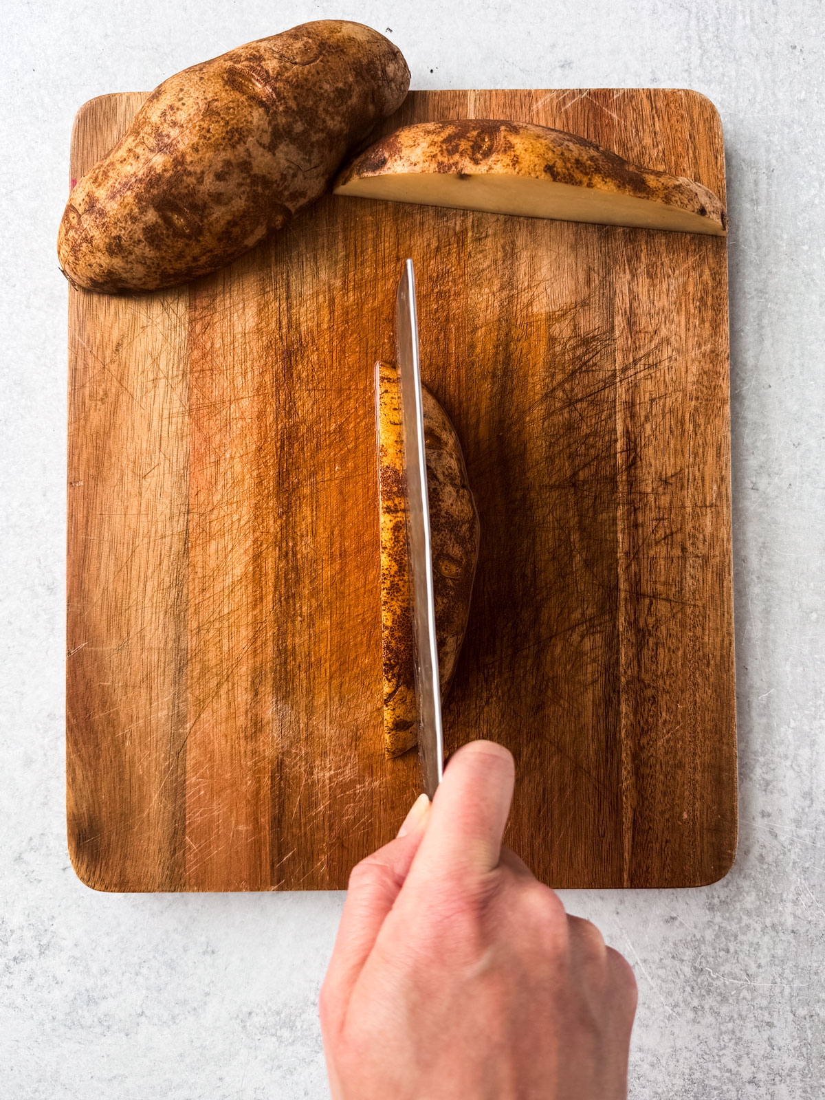 A potato half being cut into strips.