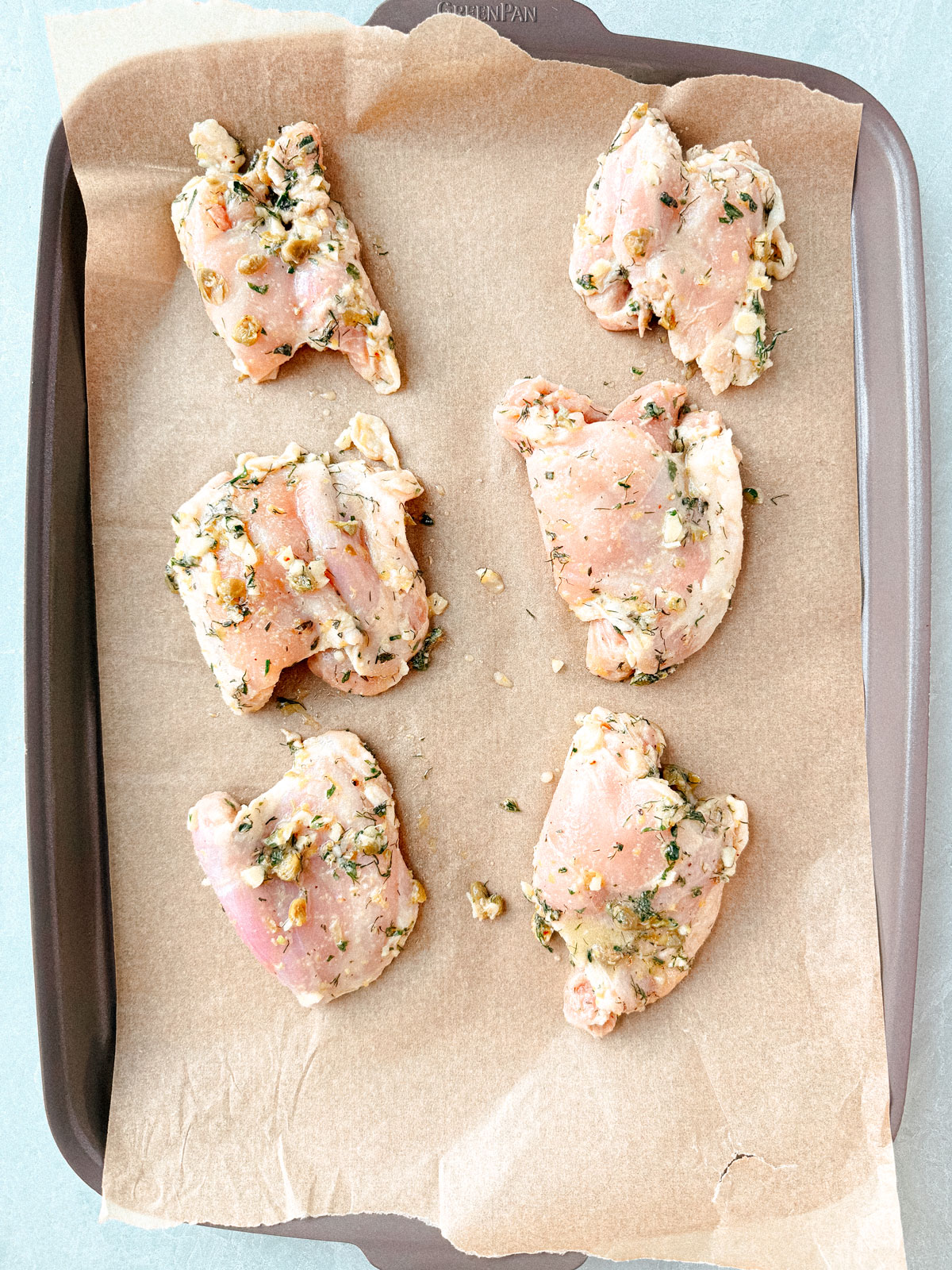 Marinated chicken thighs on a sheet pan.