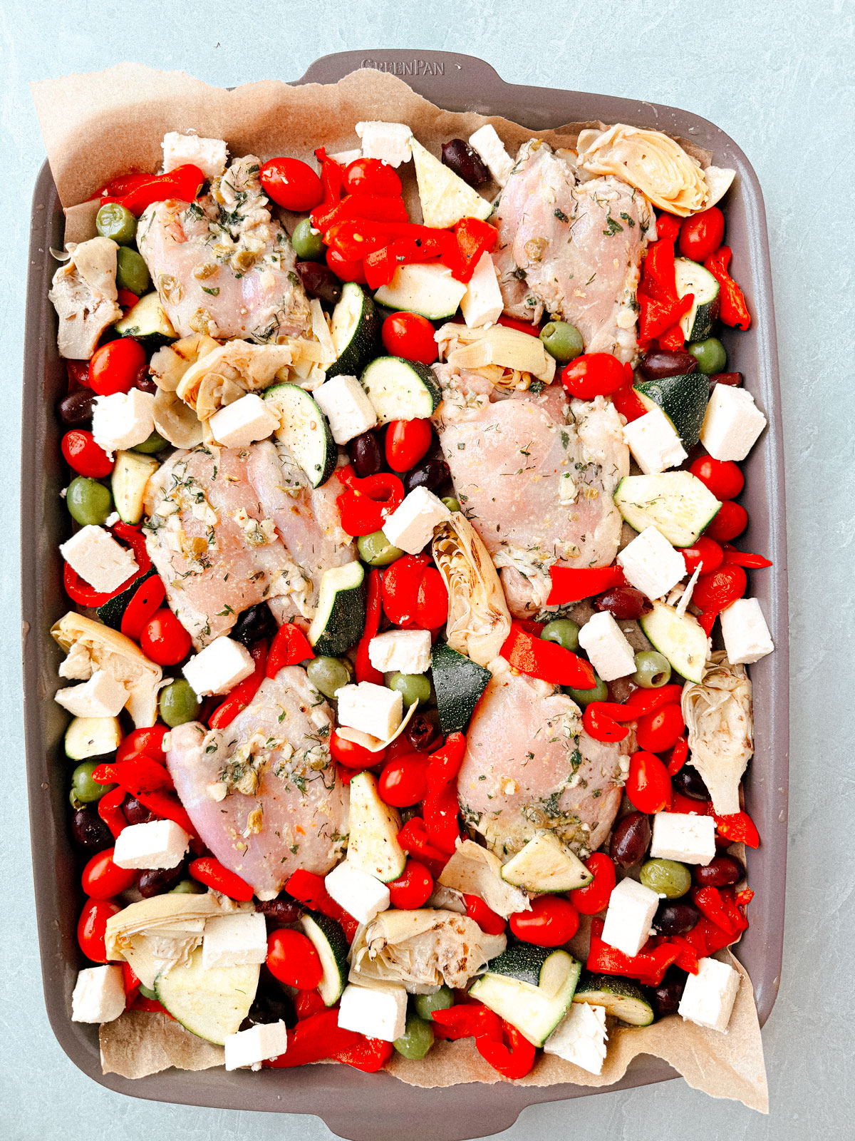 Chicken thighs and vegetables spread out on a sheet pan.