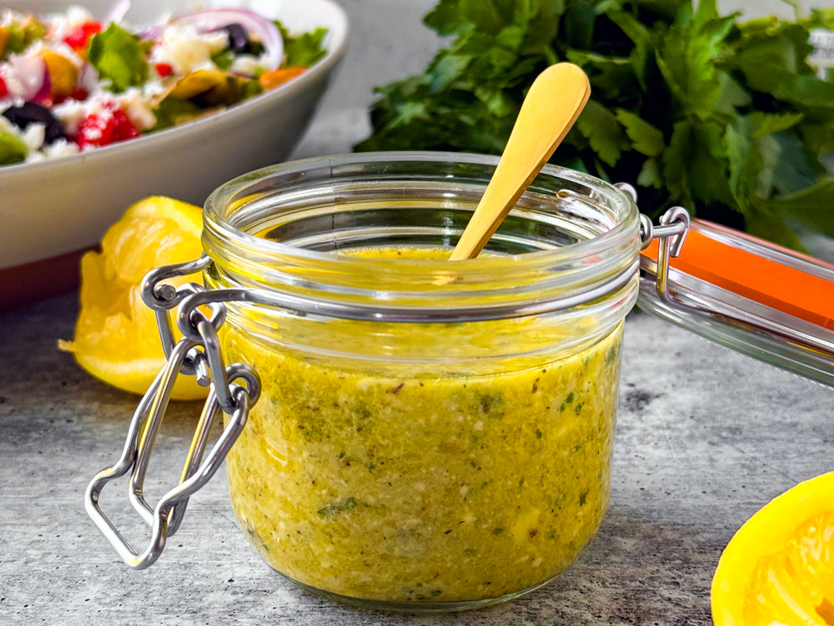 Jar of lemon vinaigrette with honey in front of a salad.