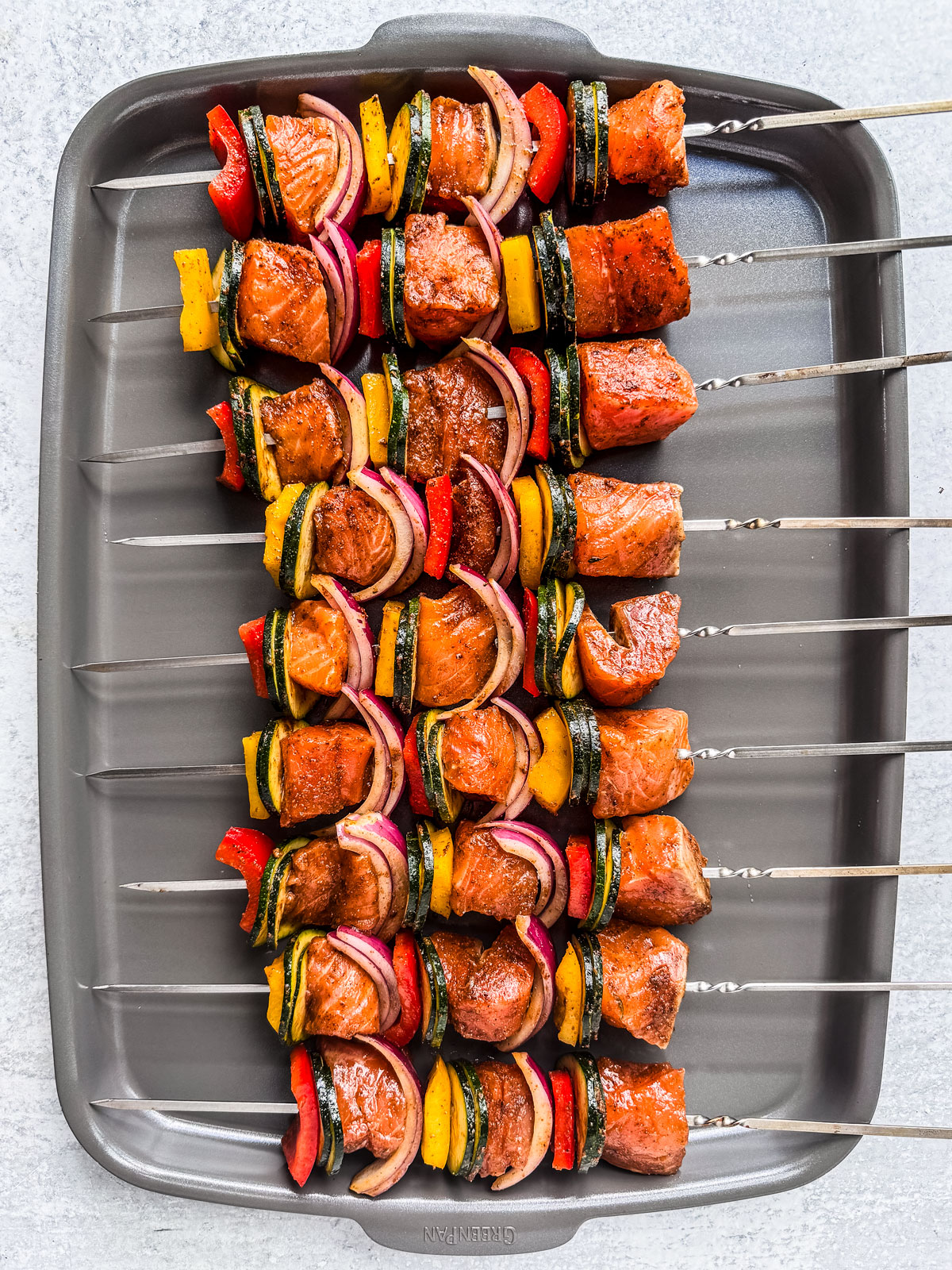 Uncooked salmon kebabs on a baking sheet.