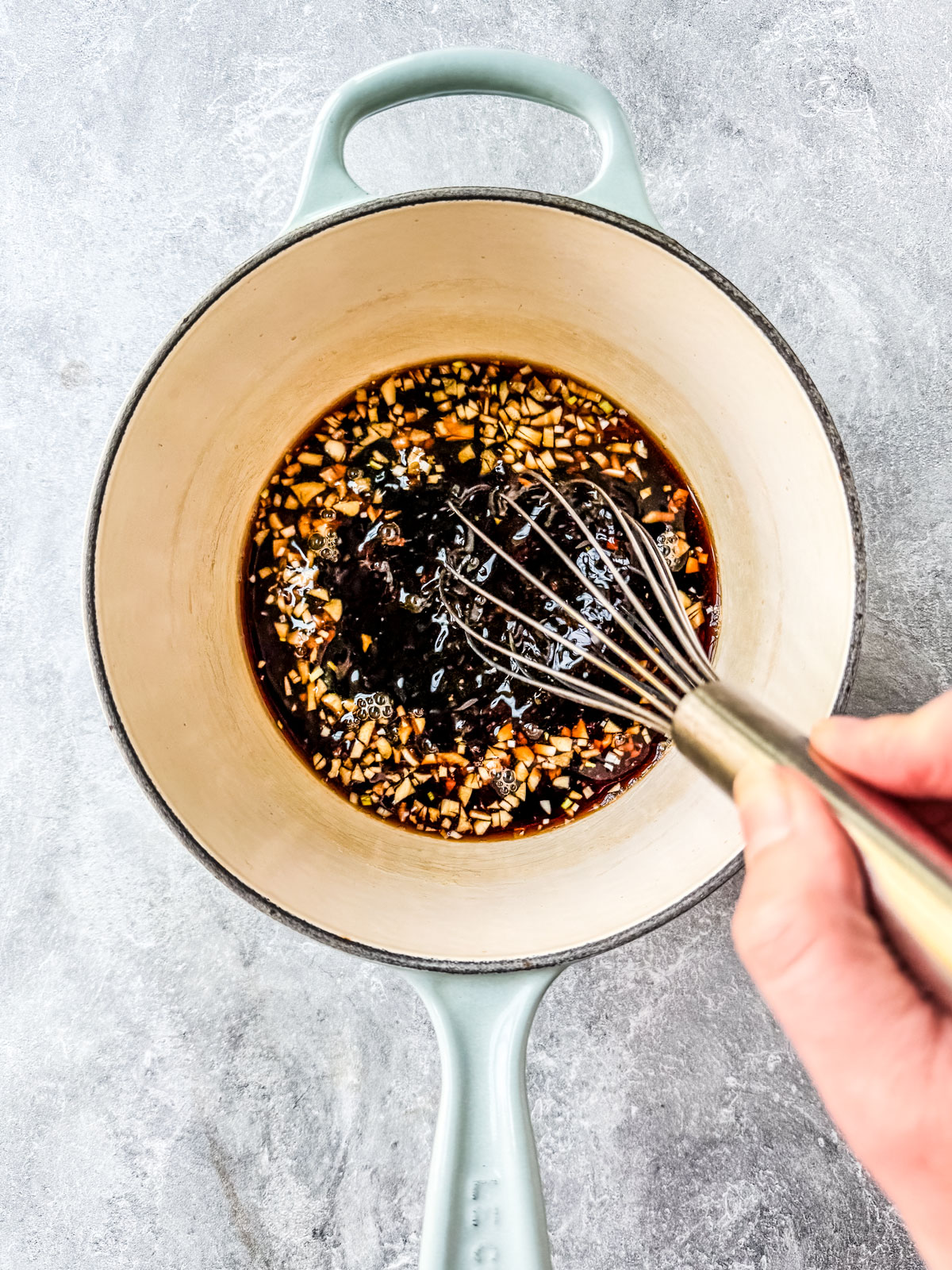 Ingredients for teriyaki sauce being whisked in a saucepan.