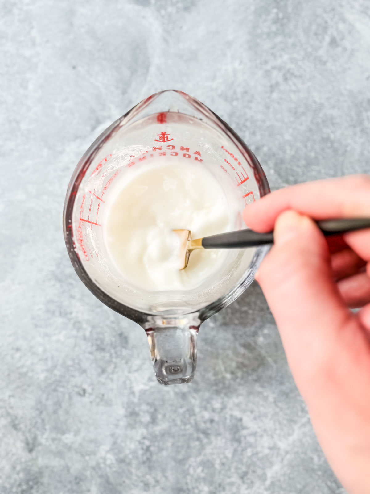 Small measuring cup of water and cornstarch being whisked into a slurry.