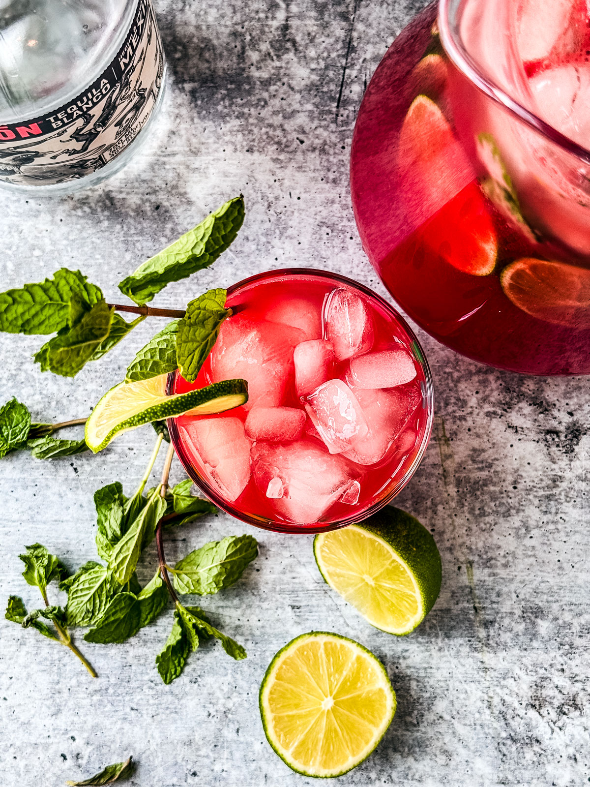 Glass of watermelon sangria garnished with lime and fresh mint.