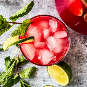 Glass of watermelon sangria over ice with limes and fresh mint.