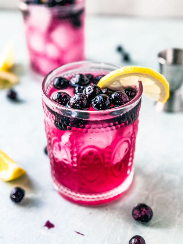 Blueberry vodka club soda in glass with lemon wedge.