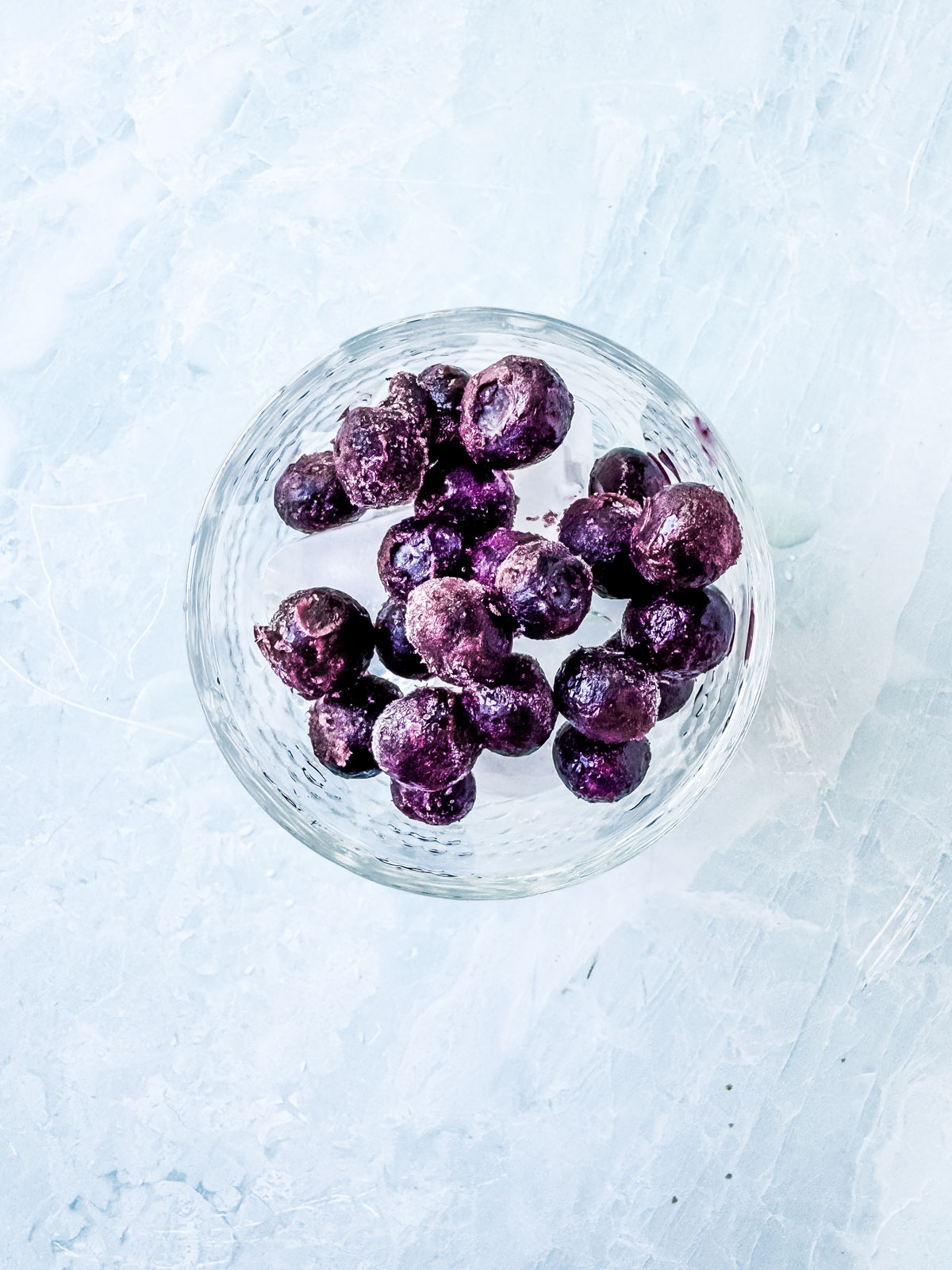 Frozen blueberries added to glass of ice.