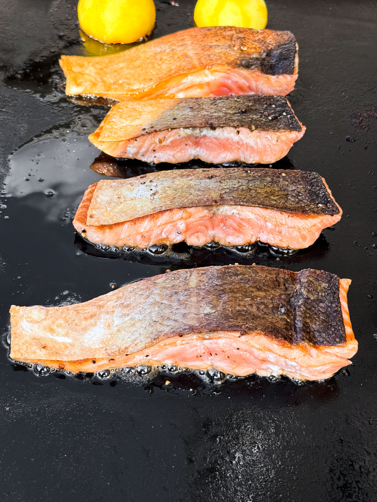 Fillets of salmon on a griddle, crispy skin-side up.