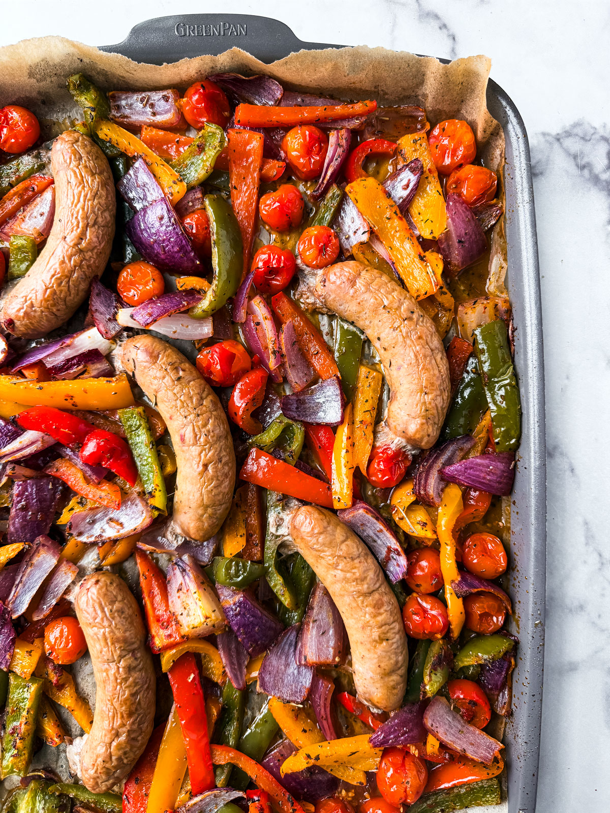 Roasted turkey sausages on a sheet pan with vegetables. 