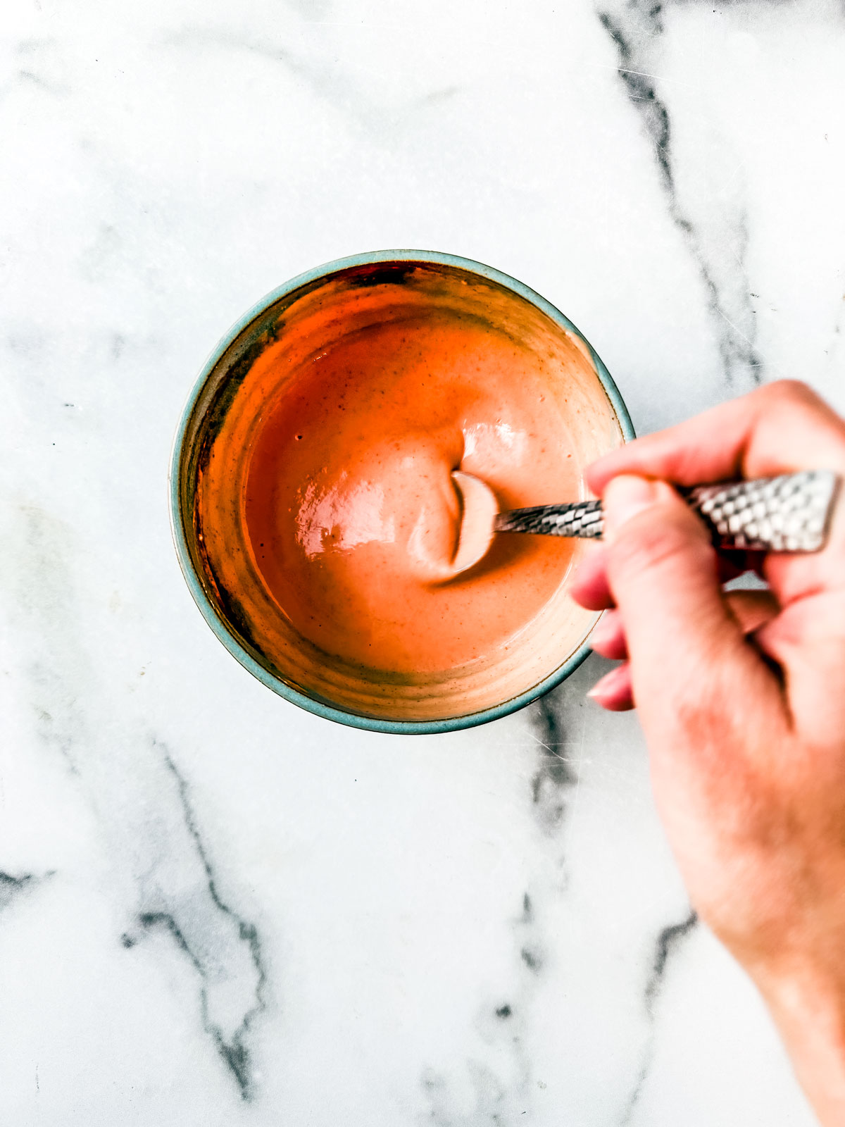 Sweet and spicy yogurt sauce being stirred. 