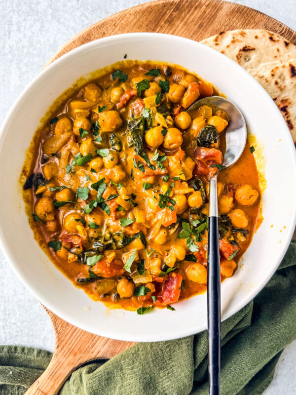 Bowl of chickpea curry with a piece of naan.