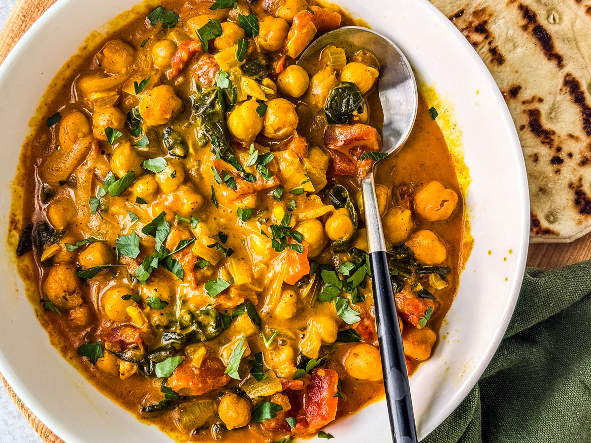 Bowl of chickpea curry with coconut milk and naan.