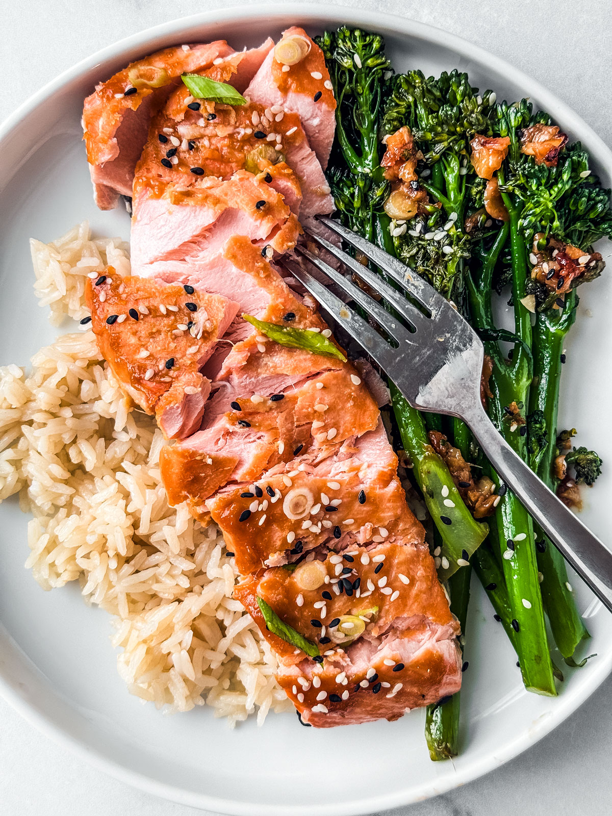 Salmon fillet flaked over rice and broccolini.