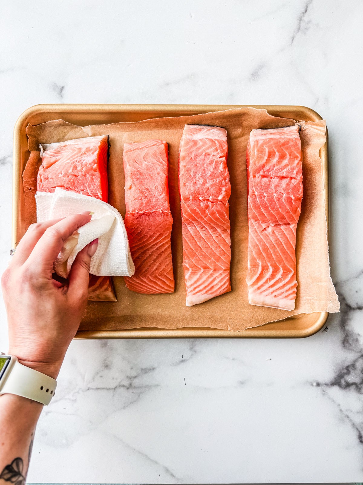 Hand blotting uncooked salmon fillets.