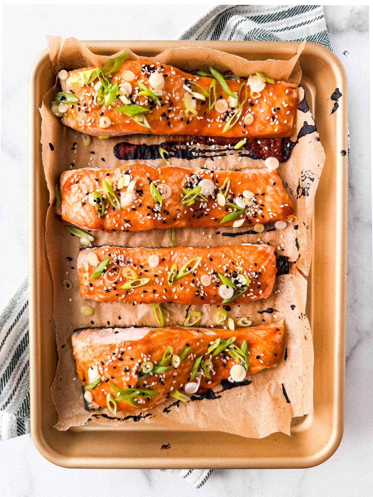 Cooked salmon fillets garnished with scallions and sesame seeds.