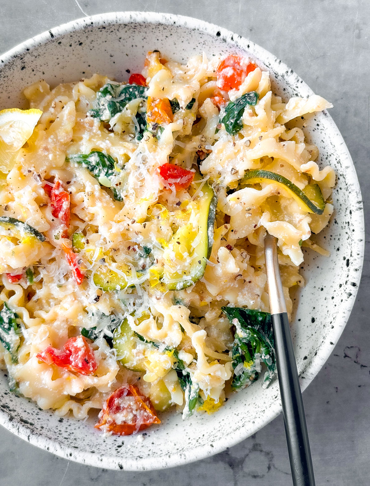 Bowl of pasta with zucchini and tomatoes.