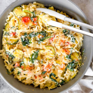 Sauté pan full of lemon ricotta pasta with zucchini.