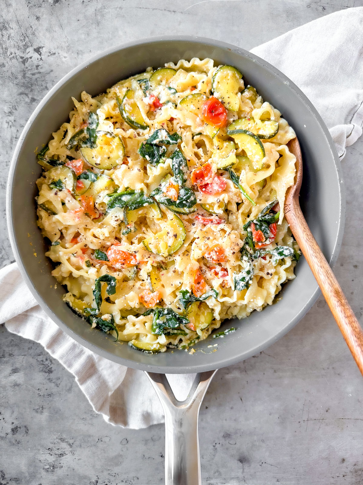 Pasta and veggies mixed into the creamy ricotta mixture in a pan.