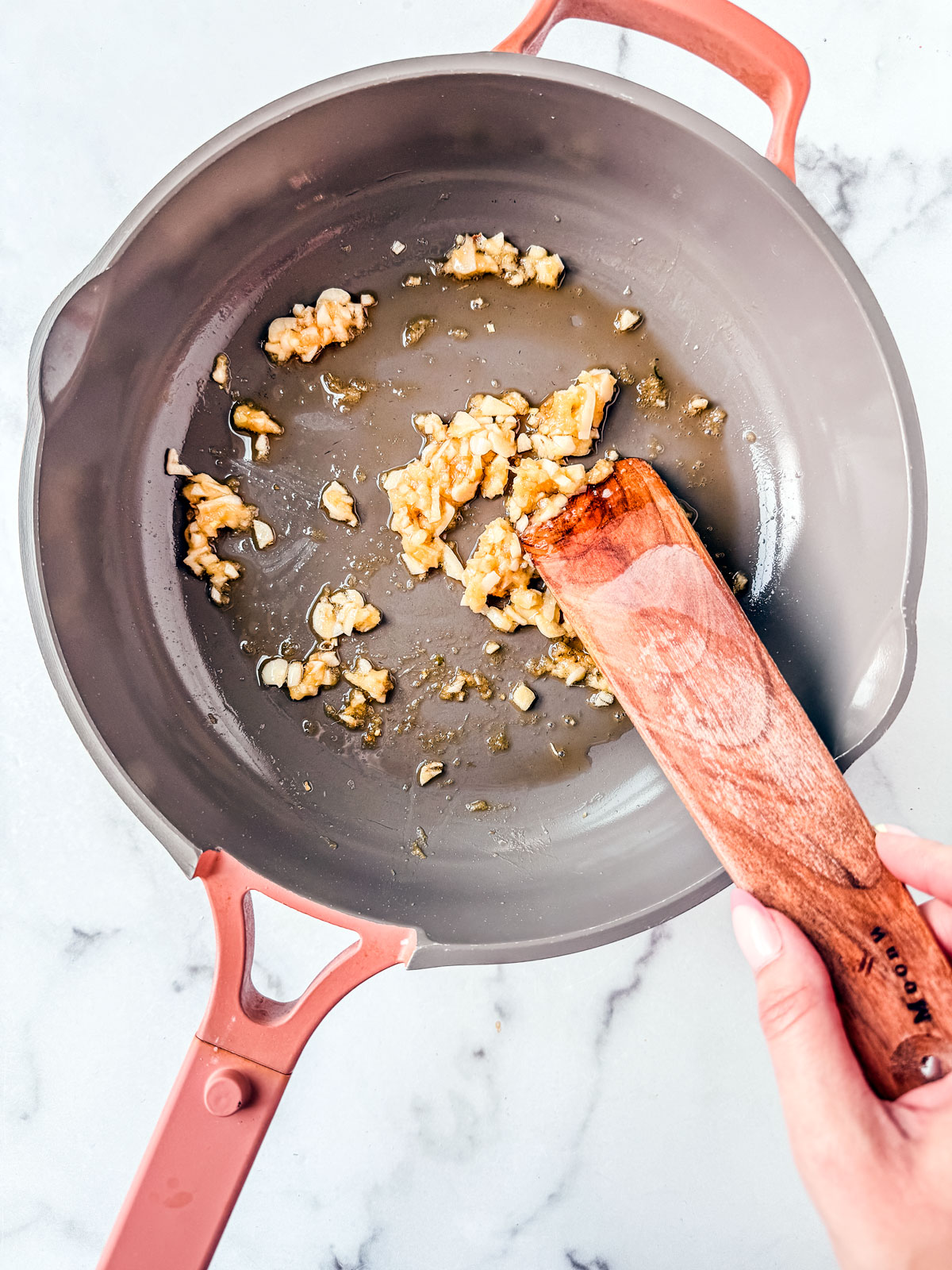 Garlic and ginger being sautéed in a pan.