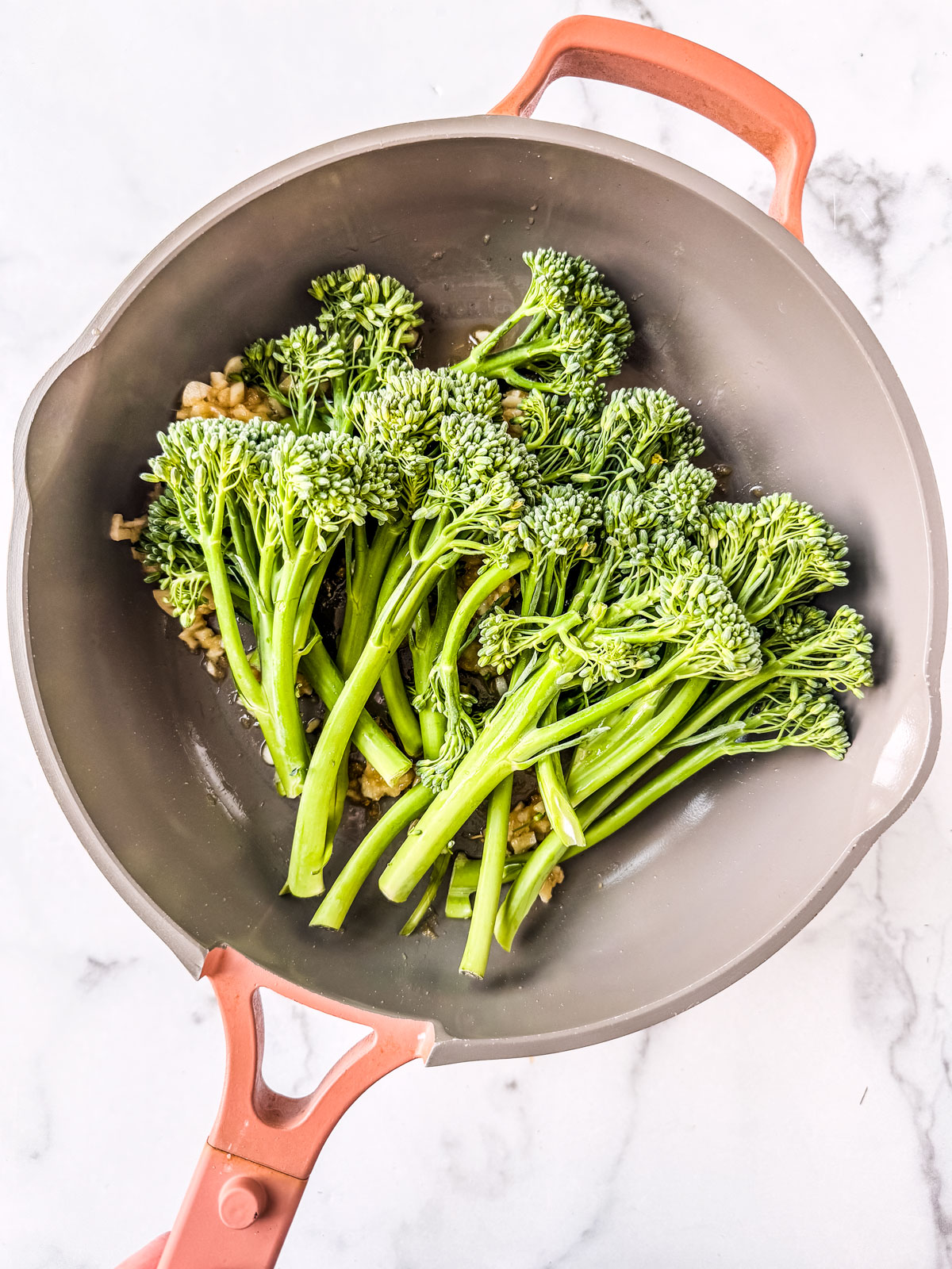 Broccolini added to the pan of garlic and ginger. 