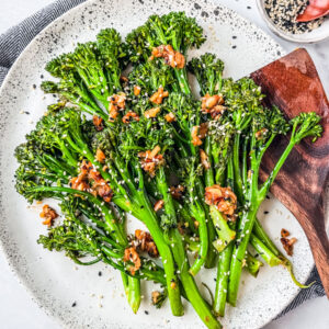 Serving plate of sauteed broccolini with a wooden spatula.