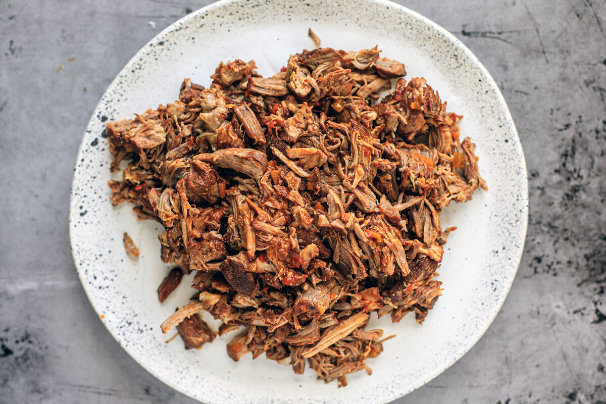 Shredded cooked pork on a white serving plate.