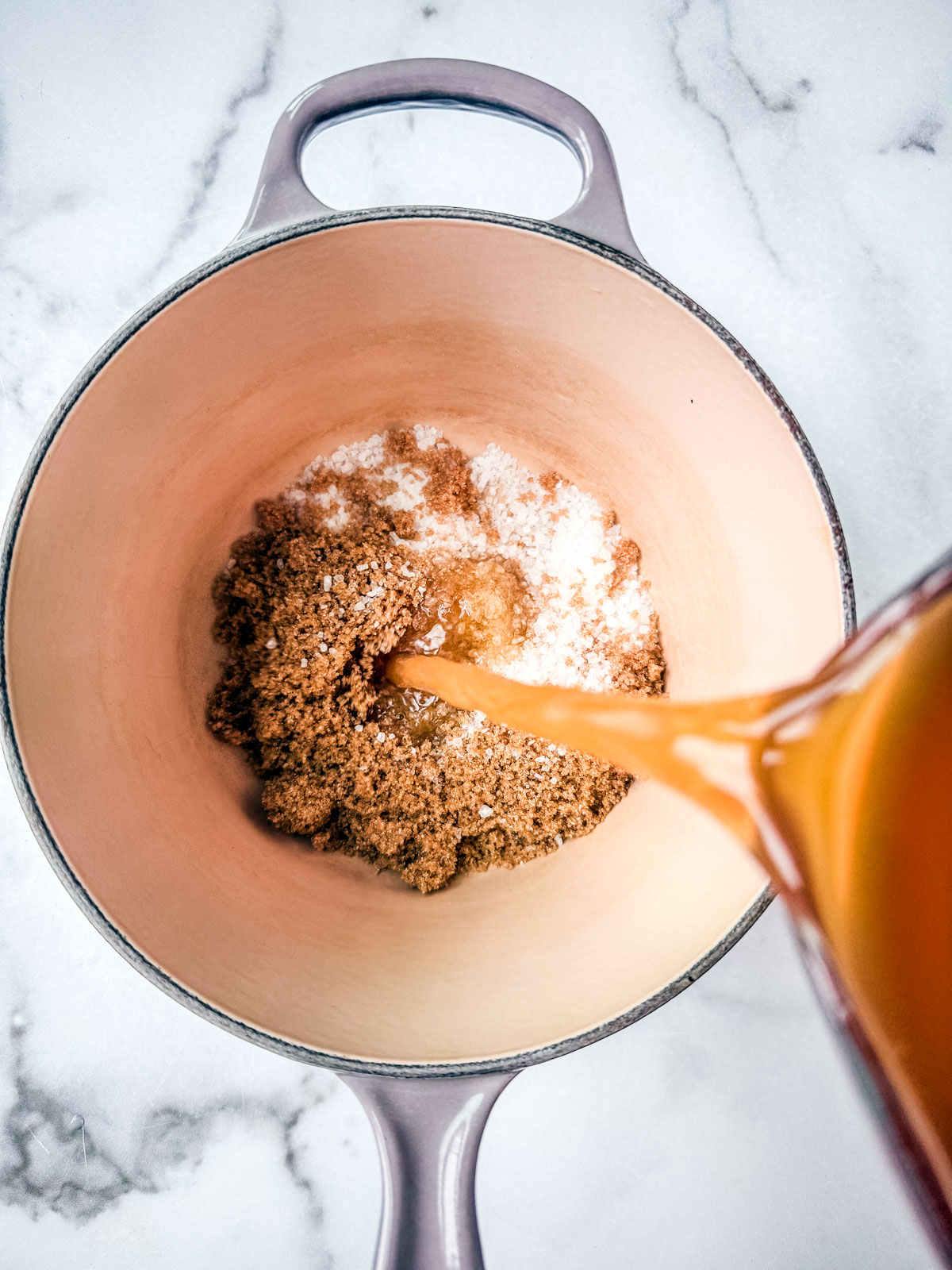 Saucepan with coarse salt and brown sugar, apple cider being poured in.