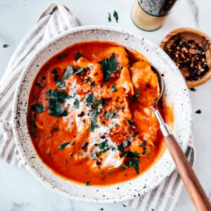 Bowl of tomato tortellini soup garnished with parsley.