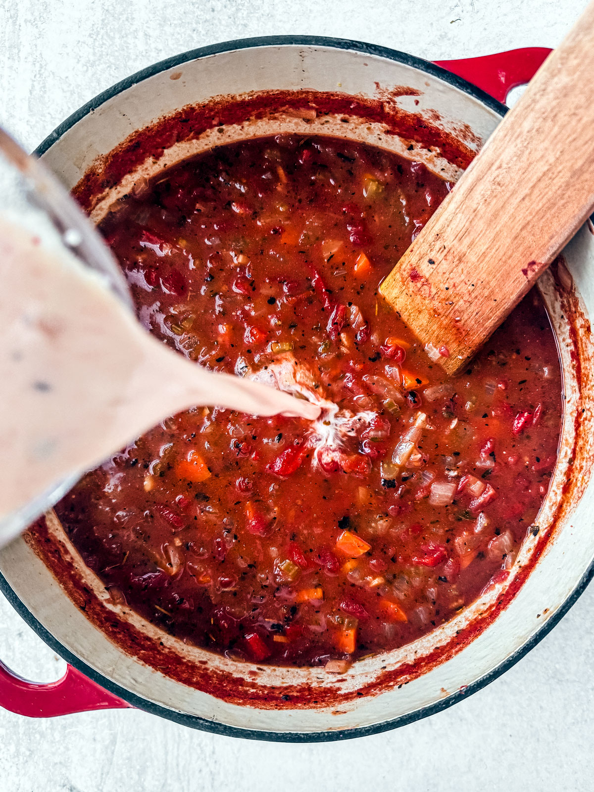 Yogurt mixture being added to tomato soup.