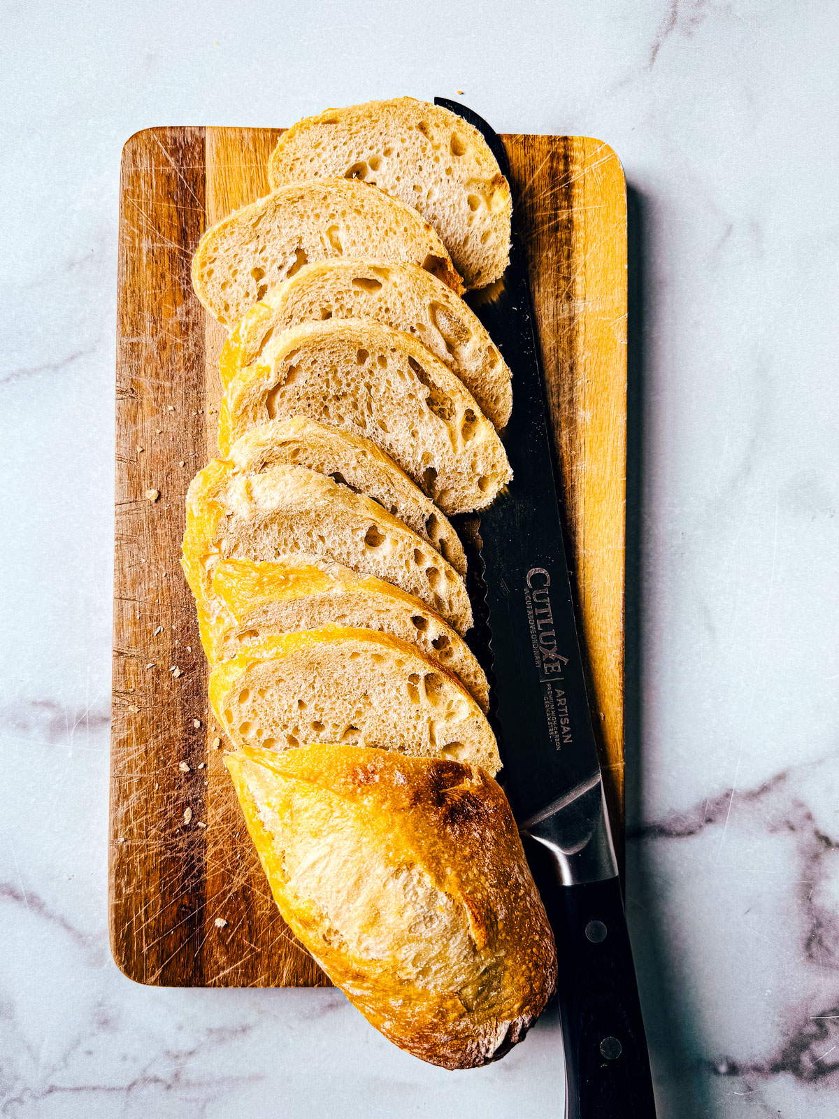 French baguette sliced on a small wooden cutting board.