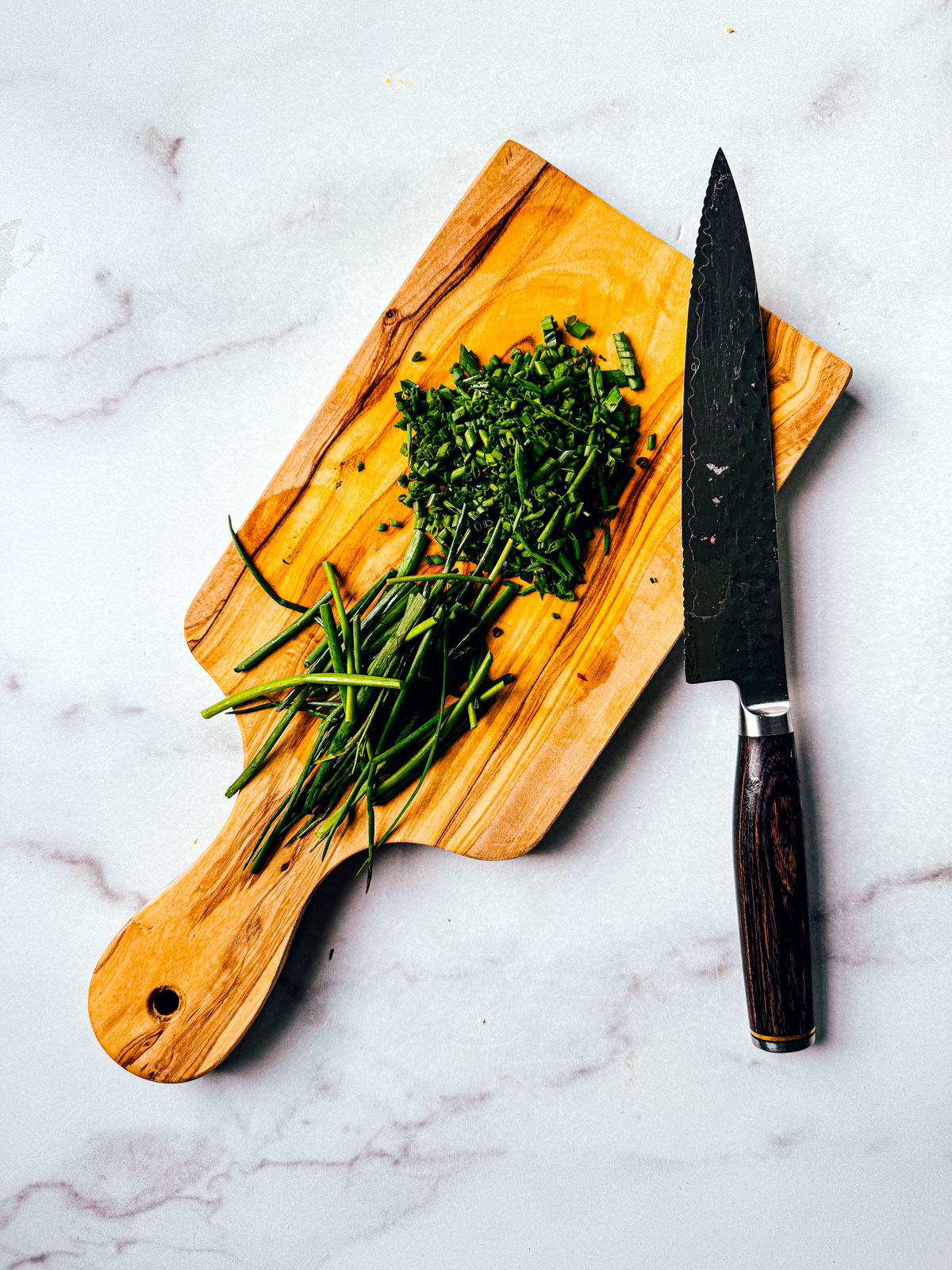 Chopped chives on a small cutting board.