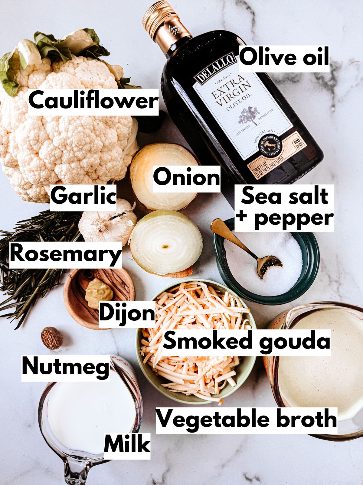 Ingredients for roasted cauliflower soup on a marble background.