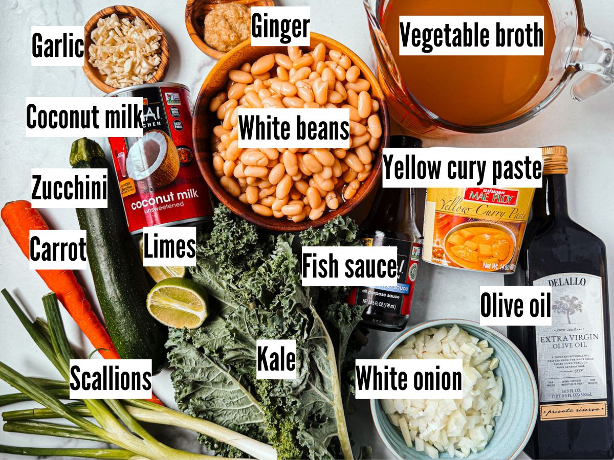 Ingredients for kale and white bean soup on a marble background.