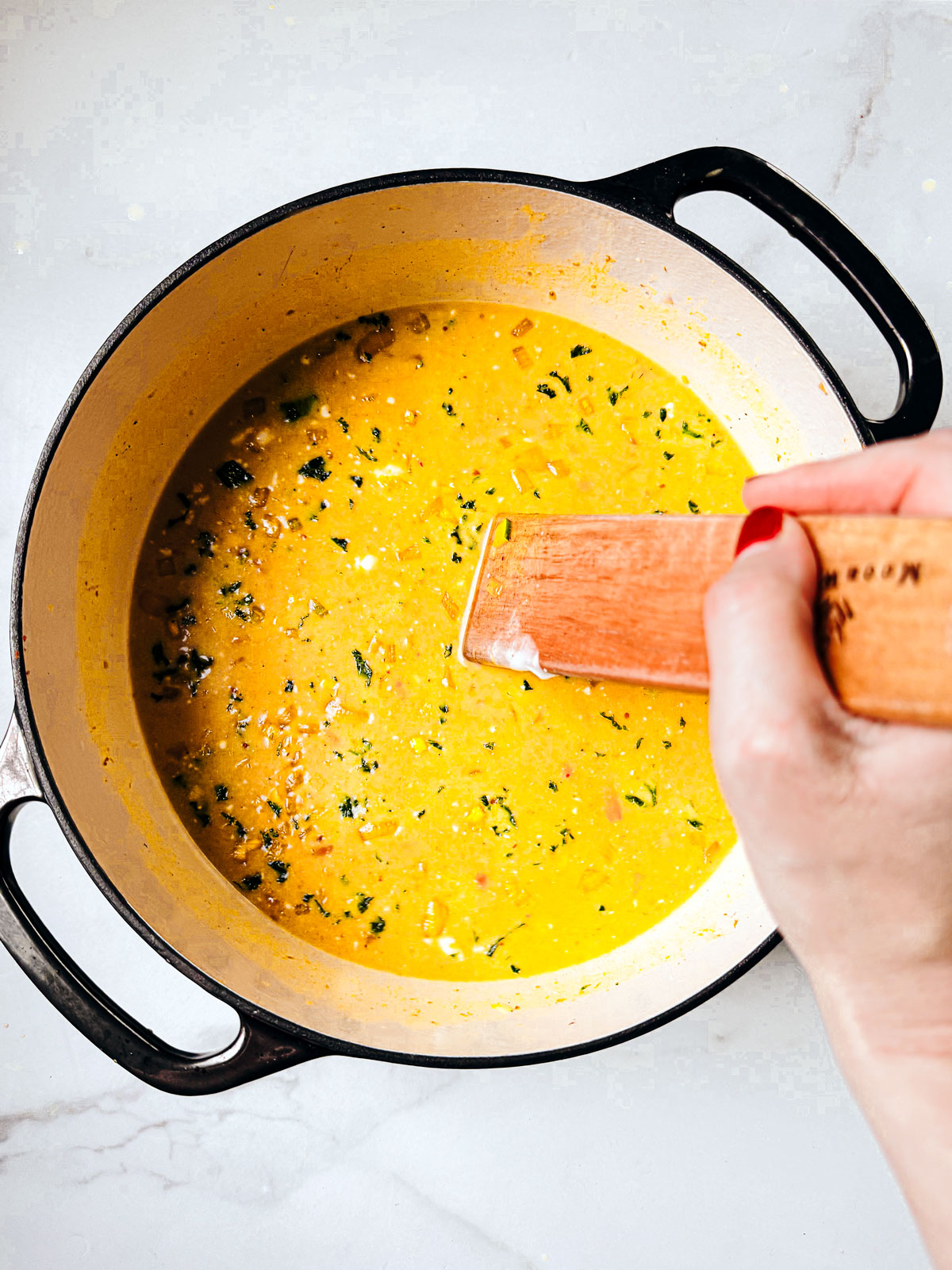 Golden soup broth being stirred.