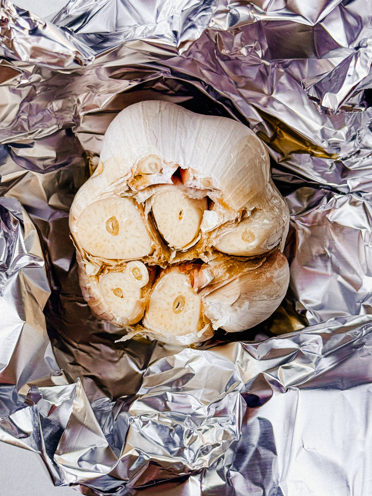 Head of garlic in tinfoil drizzled with olive oil.