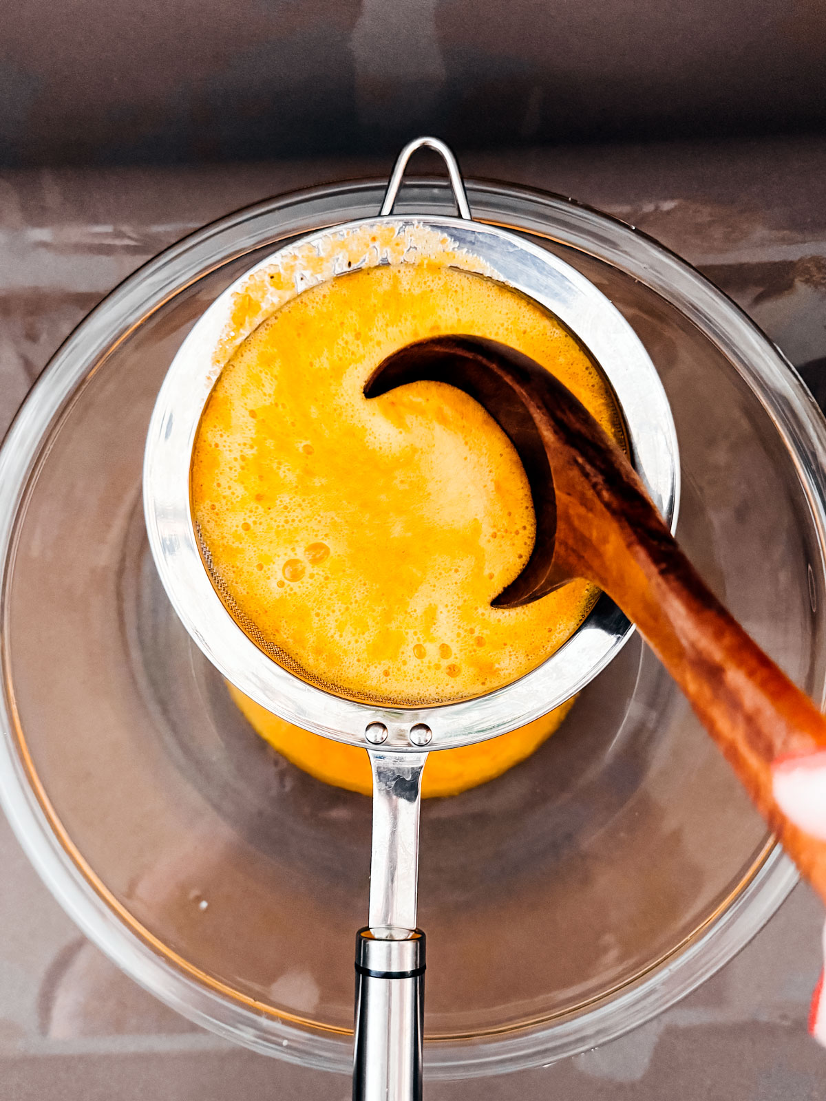 Mixture being worked through a sieve over the sink.