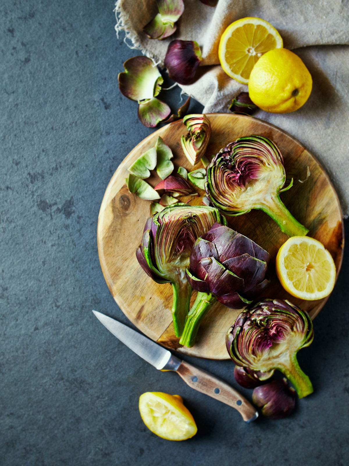 Halved fresh artichokes on a cutting board.