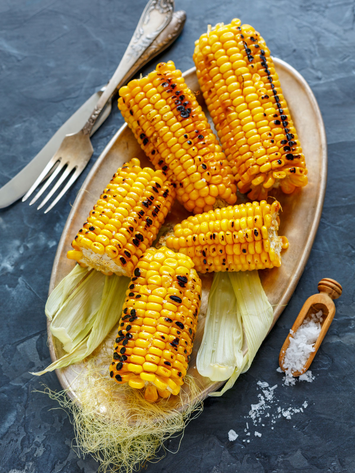 Grilled corn on the cob on a serving plate.